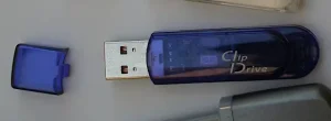 A small purplish blue semi-transparent plastic electronic device with a USB plug sticking out of it. A logo that reads "Clip Drive" is printed on it.