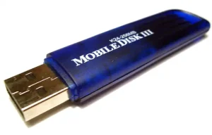 A small blue semi-transparent plastic electronic device with a metallic USB plug sticking out of it. White text on it reads K24-256MB Mobile Disk III.