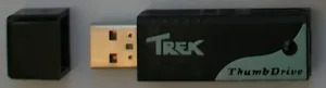 A small black plastic box with a USB plug sticking out of it. Printed on it: "Trek ThumbDrive".